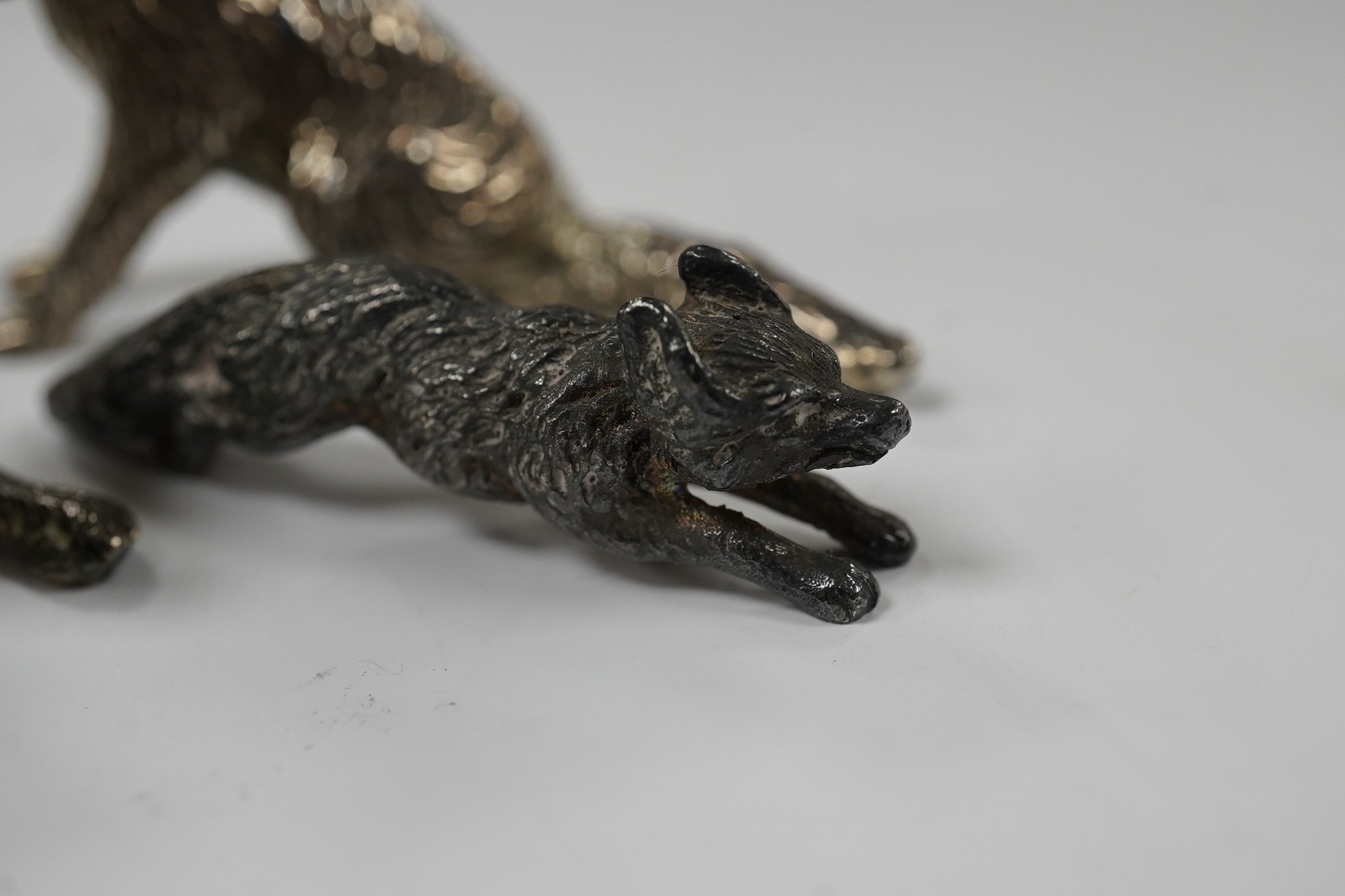 Two 1960's silver miniature models of a fox, both London, 1968, seated by Edward Barnard & Sons Ltd, height 38mm and one other smaller silver model of a running fox, 6.7oz. Condition - fair to good